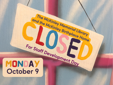 The hand-painted text on a slanted wooden hanging sign on a door window reads "Monday, October 9, CLOSED For Staff Development Day"