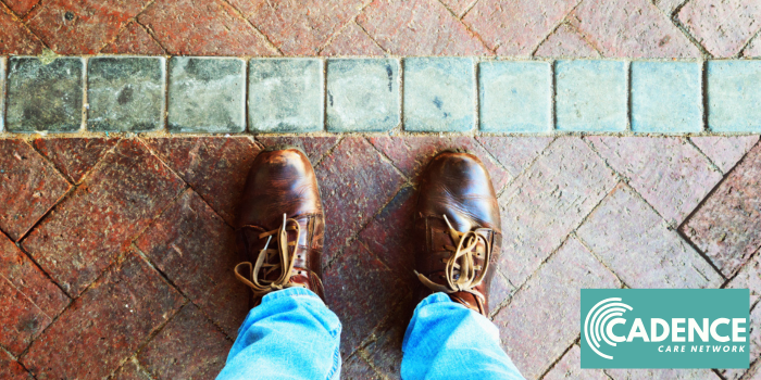 Two feet standing on a tile floor approaching a line or boundary of different color tile.